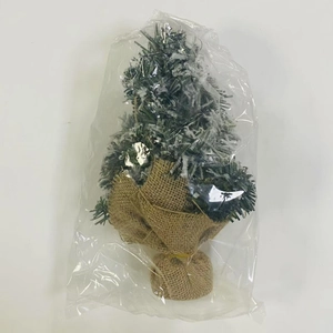 Close-up of a mini snowy Christmas tree with pine needles and rustic burlap base
