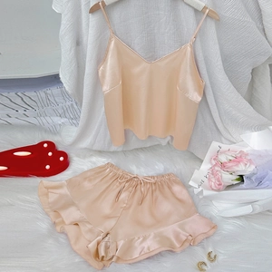 Champagne satin loungewear set with V-neck camisole and ruffled shorts on white fur rug