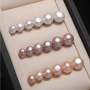 Detail of three minimalist s999 silver pearl studs in white pink and lilac colors