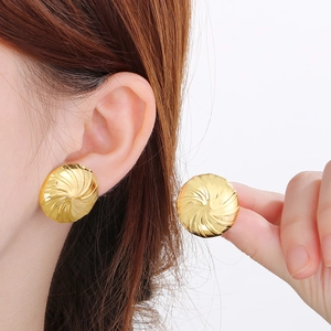 Nahaufnahme goldener Ohrstecker mit Spiraltextur, getragen von einem Modell vor weißem Grund