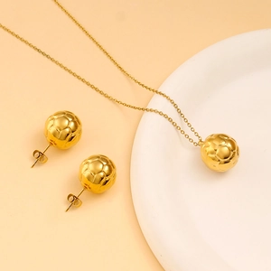 Macro shot of gold-plated soccer-shaped necklace and stud earrings jewelry set