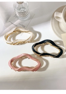 Three irregular wavy hair claws in white black and pink on a white table with soft lighting