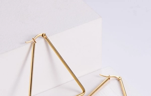 Detailed view of large gold triangular hoop earrings made of minimalist titanium steel