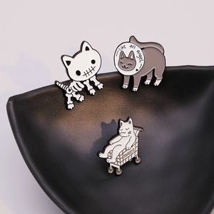 Three creative enamel cat brooches featuring quirky feline designs on matte black tray