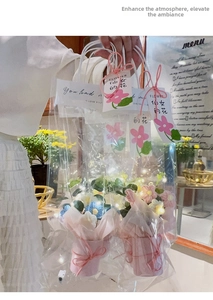 Detail of hand-crocheted floral bouquet in transparent bag with warm LED fairy lights