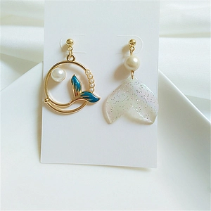 Asymmetric dolphin whale tail earrings with pearls and blue fin details on white silk