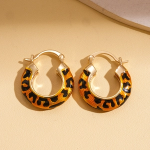 Detailed macro view of 14k gold plated leopard print hoop earrings on leather background