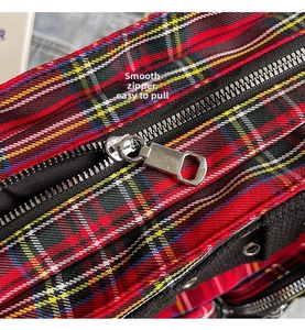 Detail view of smooth silver metal zipper on classic red plaid canvas tote bag