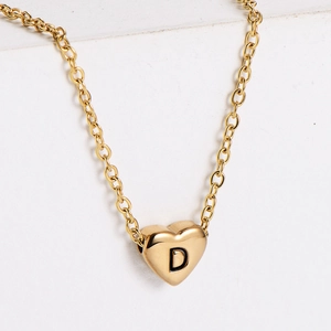 Close-up of gold heart pendant with black engraved letter D on a solid metal chain