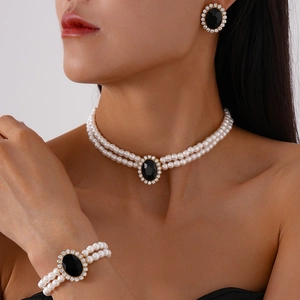 Detailed view of luxury pearl jewelry set with black oval stones on a model