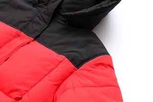 Détail des épaules bicolores rouge et noir d'une doudoune à capuche avec coutures précises