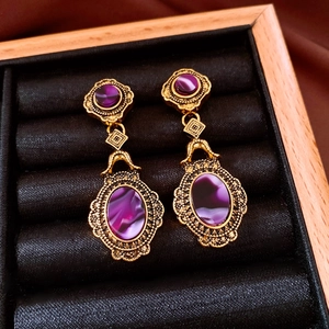Close-up of vintage gold earrings with oval purple gemstones in a velvet box