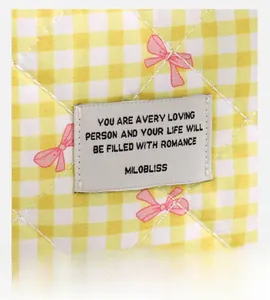 Macro detail of quilted yellow checkered fabric with bow print and decorative logo patch