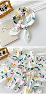 Macro view of satin silk scarf featuring cute cartoon dog and berry patterns with brand logo