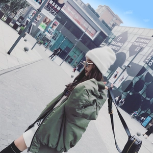 Woman wearing stylish white rabbit fur knit beanie and green bomber jacket in street style