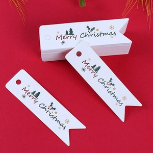 Close-up of white Merry Christmas paper tags with holiday patterns on red background