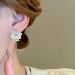 Elegant silver snowflake earrings with sparkling zircons and white pearls on female model
