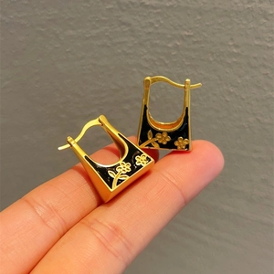 Vintage golden U-shaped hoop earrings with black enamel and floral design patterns