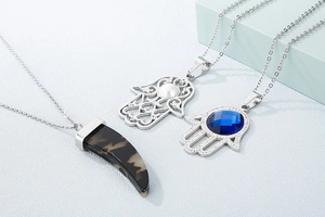 Détail des pendentifs main de Hamsa et corne avec gemme bleue et éclats de cristal