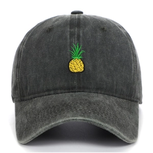 Detailed close-up of yellow pineapple embroidery on washed black cotton baseball cap