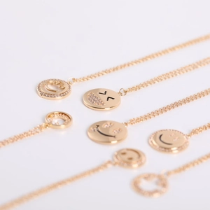 Macro detail of gold-plated smile face pendants with micro-pave cubic zirconia inlay