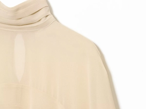 Gros plan du col plissé et découpe sur un chemisier en georgette beige doux