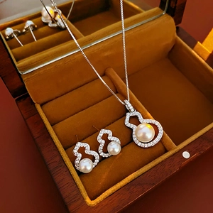 Macro shot of silver pearl gourd necklace and earrings set in a wooden jewelry box