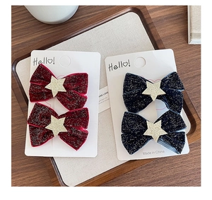 Close-up of velvet bow hair clips with glitter stars in red and navy blue on card