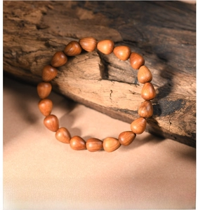 Macro shot of polished teardrop-shaped wood beads with natural grain on wooden background