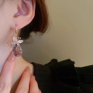 Close-up of zircon butterfly and purple water drop earrings on a female model's ear