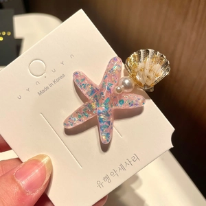 Close-up of ocean-style hair clip with pink sequin starfish, pearls, and a seashell