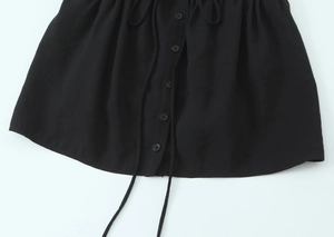 Close-up of black woven fabric featuring decorative buttons and long drawstring details