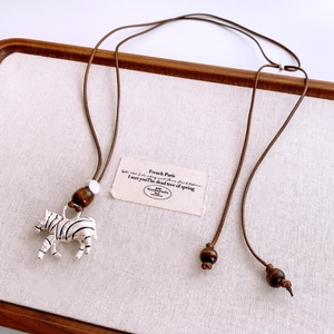 Close-up of vintage zebra pendant with brown wood beads on rustic linen display