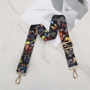 Detailed view of wide replacement bag strap with colorful butterfly pattern and gold hardware