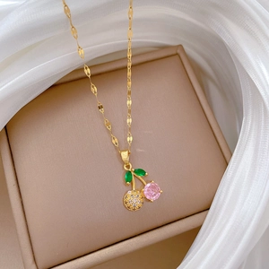 Macro detail of a cherry pendant necklace featuring pink gemstones and green leaves