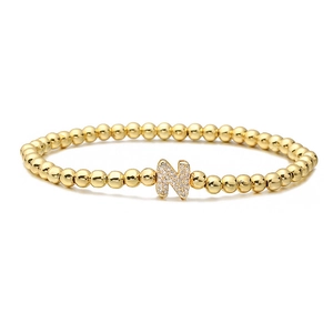 Detail of beaded gold bracelet featuring a micro-paved letter N pendant with white zircons