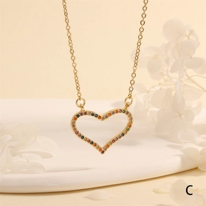 Detail of hollow heart pendant with multicolor zircon inlay on thin gold chain necklace