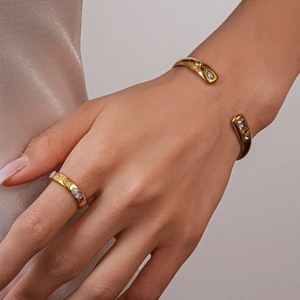 Detailed shot of golden sun-teardrop bangle and ring set with sparkling zircon stones
