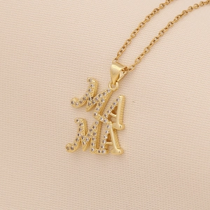 Golden MAMA heart necklace with inlaid stones on a textured beige fabric background