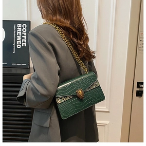 Detail of green crocodile pattern shoulder bag with gold chain and lion head buckle