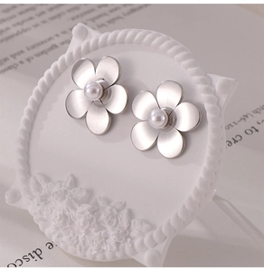 Gros plan détaillé de boucles d'oreilles fleur argent mat avec perles sur un présentoir