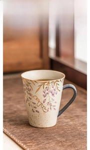 Macro detail of wisteria floral pattern and golden rim on handmade ceramic mug
