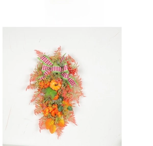 Detail of autumn wreath with checkered bow, faux pumpkins, maple leaves, and berries