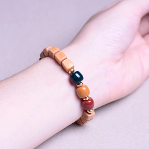 Detail of sandalwood square beads bracelet with green and red ceramic spacers on wrist