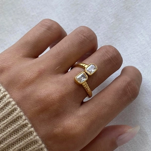 Detail of elegant gold double-stone open ring on a model hand with warm lifestyle lighting