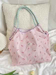 Pink checkered tote bag with red bow prints and purple ruffle trim on white bedding