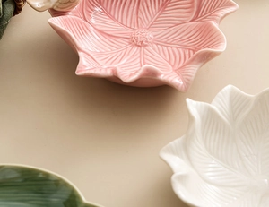 Detailed top view of three leaf-shaped ceramic jewelry plates in pink, white, and green colors