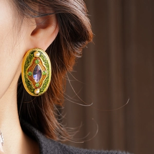 Detail of vintage oval earrings with green enamel floral patterns and purple rhinestones