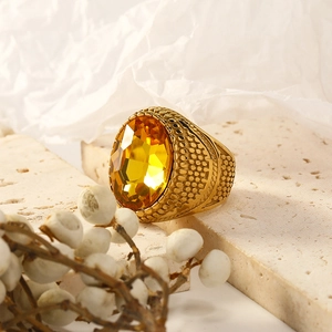 Macro shot of an oval yellow gemstone on a gold-plated stainless steel ring with textures