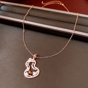 Macro shot of rose gold gourd pendant with tiger eye stone and pearls on a jewelry box